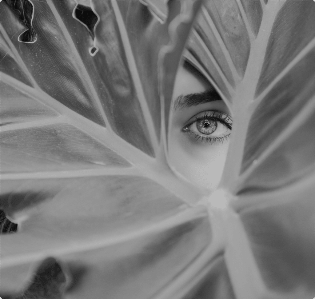 Une femme cachée derrière une grande feuille